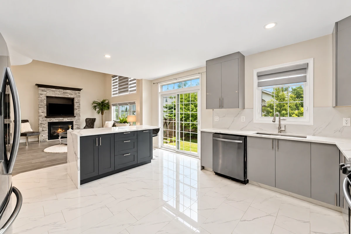 Open-concept Ottawa kitchen with a dark island, grey cabinetry and bright patio doors